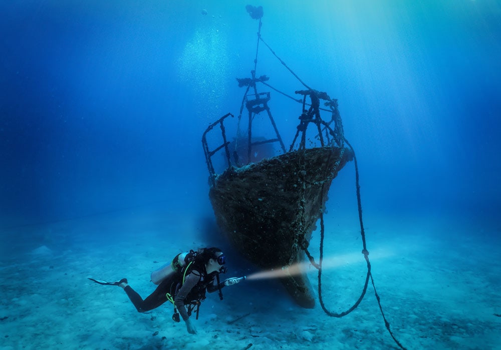 A female scuba diver explores a sunken shipwreck