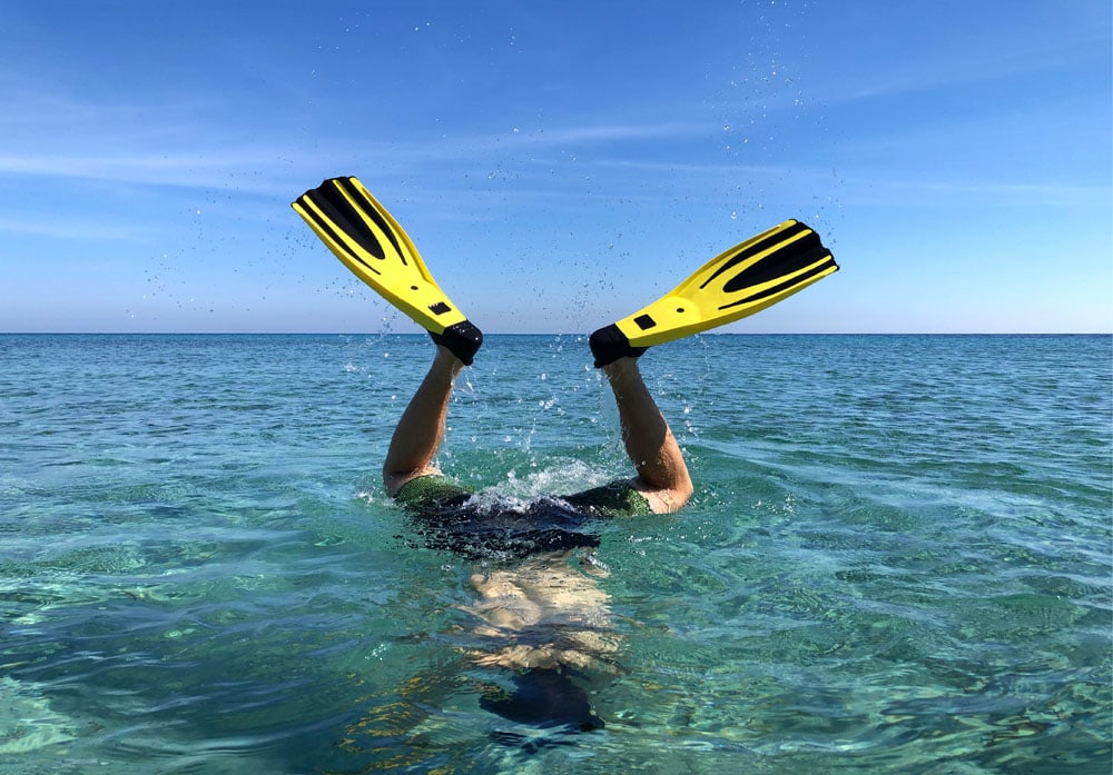 Male legs with flippers in the sea.