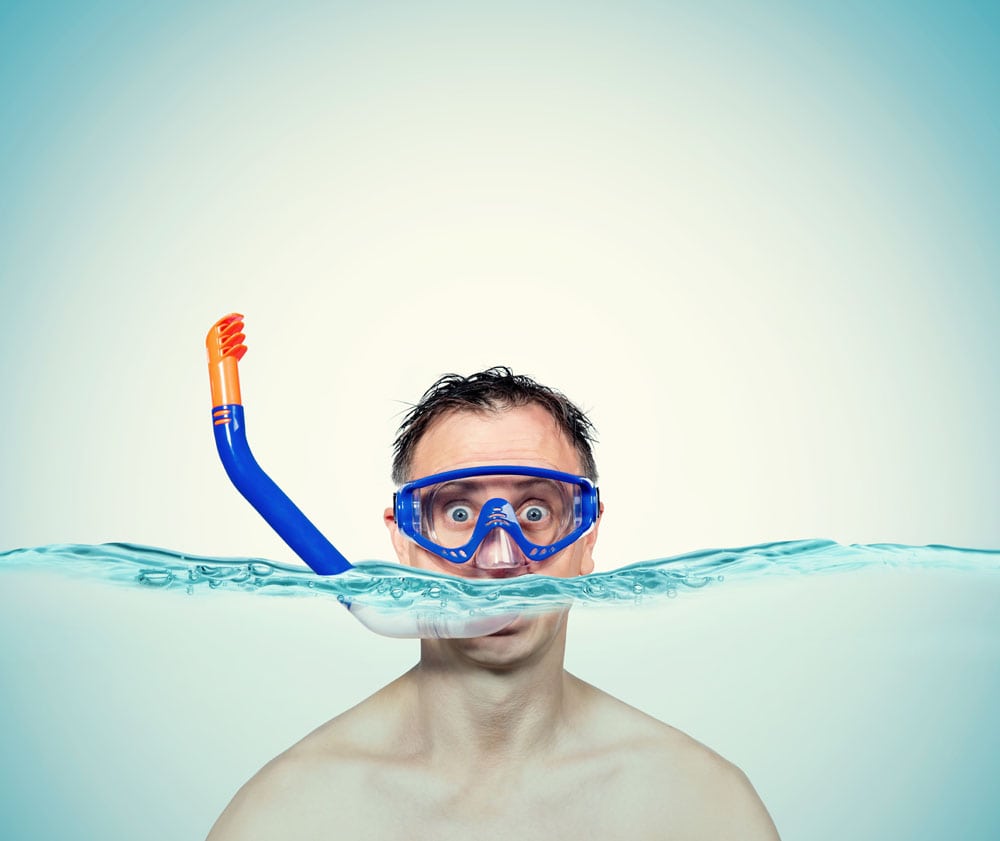 Happy funny man in a swimming mask awith snorkel is in the water. Sea holiday concept.