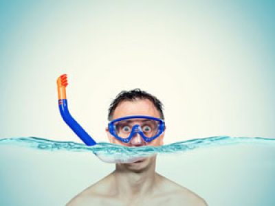 Happy funny man in a swimming mask awith snorkel is in the water. Sea holiday concept.